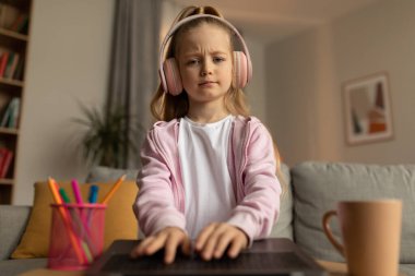 Eğitimsel sorunlar. Diz üstü bilgisayar kullanan, kulaklık takan, evde bilgisayar başında oturmayı öğrenen liseli kız memnun değil. E-Öğrenme Konsepti. Ön Görünüm