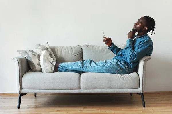 Thoughtful Black Man Using Mobile Phone Sitting Sofa Home Side — Foto de Stock