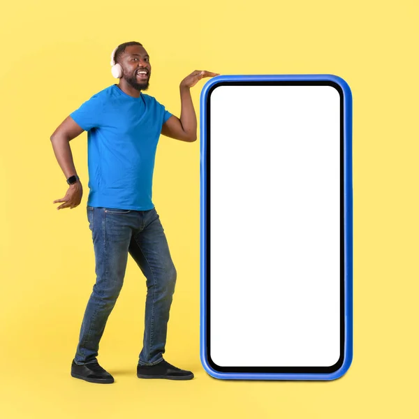 Cheerful Black Male Dancing Huge Smartphone Blank Screen Yellow Studio — Stockfoto