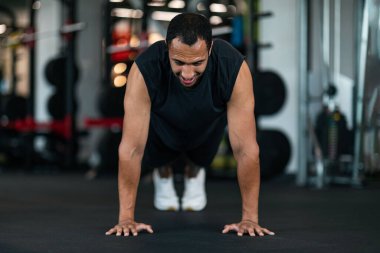 Athletic Black Man Making Floor Push Up Exercise While Training In Gym, Muscular African American Male Exercising In Modern Sport Club, Practicing Bodybuilding, Front View With Copy Space