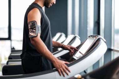 Smiling Black Male Athlete Choosing Jogging Mode While Training On Treadmill, Side View Shot Of Young Sporty African American Man Exercising With Modern Equipment In Fitness Club, Copy Space
