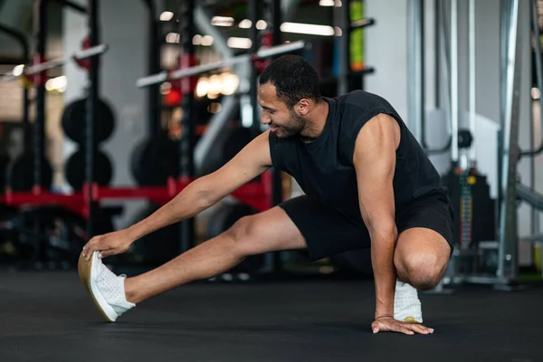 Sporty Young Black Man Stretching Leg Muscles While Training Gym — Stockfoto