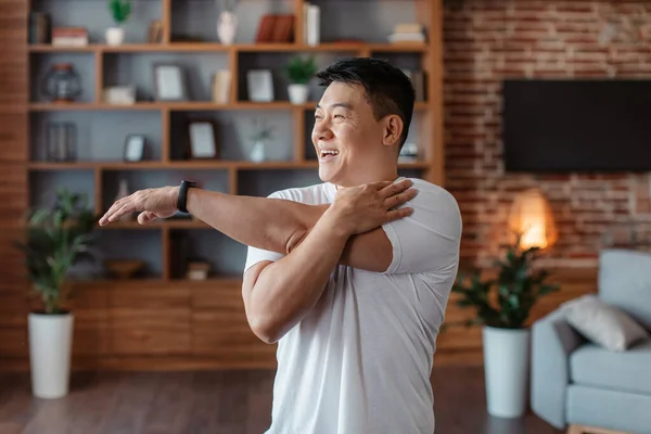 Active Asian Mature Man Stretching Arm Muscles Doing Warmup Exercises — Foto de Stock