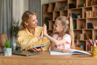 Well done. Excited teacher giving high five to little girl, greet schoolgirl for giving correct answer solving hard math problem, praise child for reaching success in homework