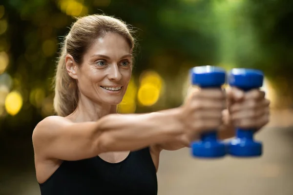 Closeup Photo Motivated Sporty Woman Exercising Small Blue Dumbbells Outdoors — Stock fotografie