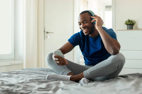 Cheerful African American Man Listening Music Wearing Headphones Sitting Bed — Foto de Stock