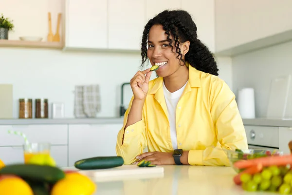 Happy Black Woman Cooking Fresh Vegetable Salad Biting Cucumber While — 스톡 사진