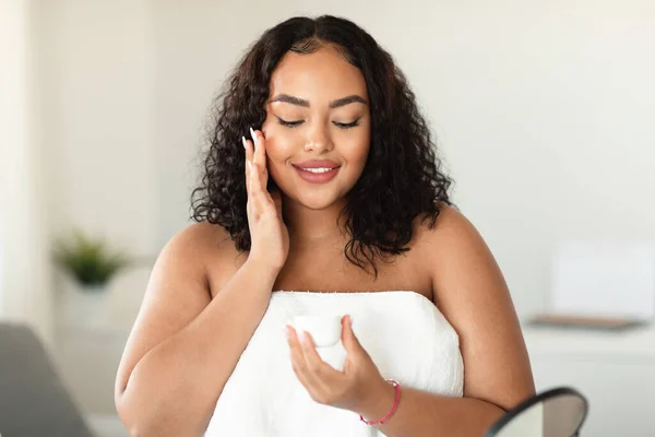 Black Size Woman Applying Hydrating Cream Her Face Holding Jar — Stok Foto