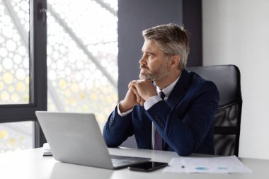 Pensive Middle Aged Entrepreneur Pondering Business Ideas While Sitting At Desk In Office, Portrait Of Thoughtful Mature Businessman At Workplace, Man In Suit Leaning Chin On Hands And Looking Away