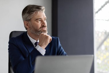 Business Planning. Portrait Of Thoughtful Mature Businessman At Workplace In Office, Pensive Middle Aged Manager In Suit Sitting At Desk With Laptop Computer And Looking Away, Closeup Shot