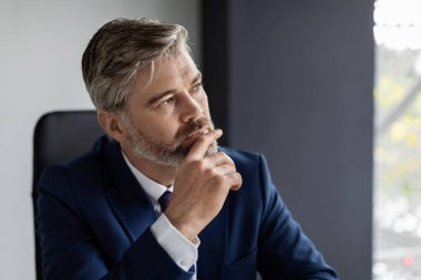 In Search Of Inspiration. Thoughtful Middle Aged Businessman Sitting At Workplace In Office, Closeup Shot Of Pensive Mature Male Entrepreneur In Suit Touching Chin And Looking Away, Free Space