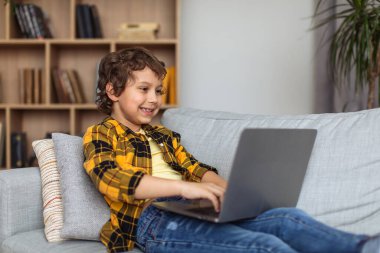 Cyber safety for kids. Young excited little boy typing on laptop, exploying internet at home, watching forbidden websites alone, free space