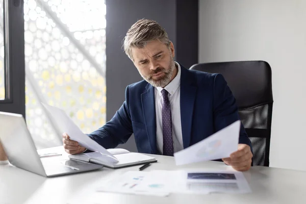 Thoughtful Mature Businessman Working With Papers At Desk In Modern Office, Busy Middle Aged Male Entrepreneur Wearing Suit Reading Financial Documents, Checking Company Annual Reports, Free Space