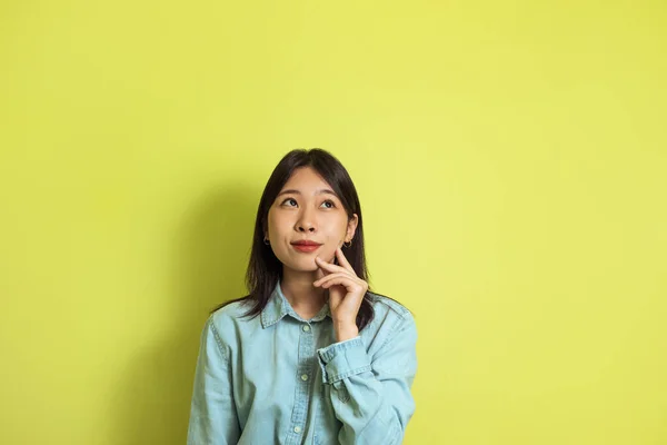 Thoughtful Asian Female Thinking Posing Looking Aside Standing Yellow Studio — Stock Fotó