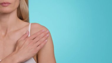 Skin treatment. Close up shot of unrecognizable caucasian woman rubbing gel on her shoulder, blue studio background, slow motion, empty space