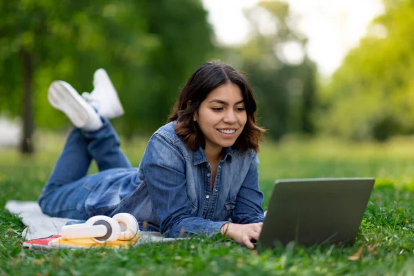 Smiling Arab Female Student Using Laptop While Lying Lawn Outdoors — Foto Stock