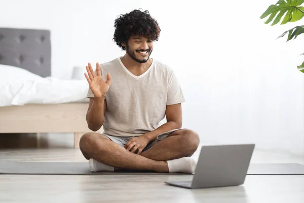 Happy Eastern Millennial Guy Sitting Yoga Mat Bedroom Home Waving — Zdjęcie stockowe