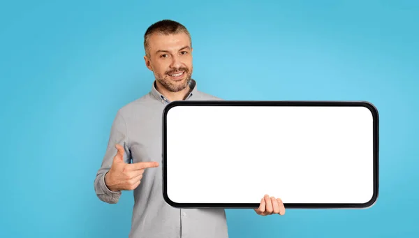 Cheerful Middle Aged Man Holding Large Smartphone Empty Screen Pointing — Stock Fotó