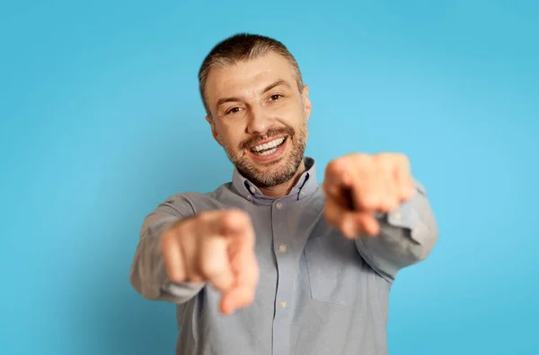I Choose You. Cheerful Middle Aged Man Pointing Fingers At Camera With Both Hands Posing Standing Over Blue Background, Studio Shot. Look At You Concept. Selective Focus
