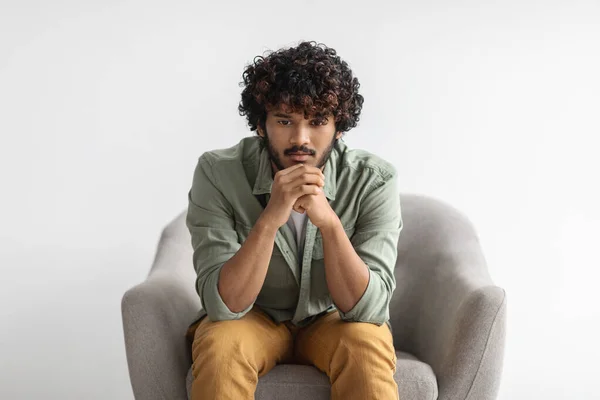 Pensive Curly Bearded Young Indian Guy Casual Outfit Sitting Armchair — 图库照片