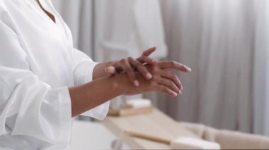 Dry skin treatment. Side view shot of unrecognizable african american lady applying pampering cream on her hands at bathroom, selective focus, free space