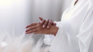 Beauty care at home. Close up shot of unrecognizable black lady wearing bathrobe rubbing pampering cream on her hand skin, selective focus, free space