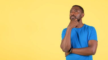 Let Me Think. Thoughtful African American Man Thinking Looking Aside At Empty Space For Text Posing Touching Chin Standing Over Yellow Background. Panorama, Studio Shot