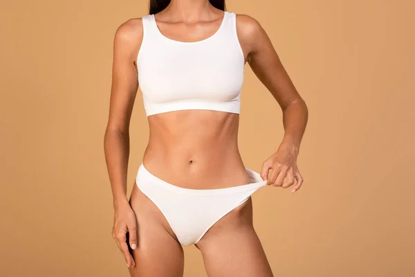 Fit Woman Wearing White Lingerie Pulling Panties Standing Isolated Beige — Stockfoto