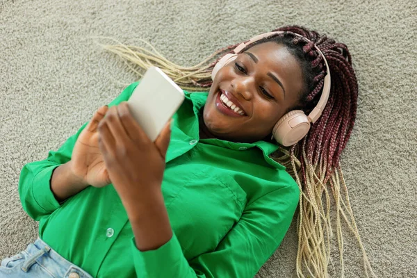 Happy African American Lady Headphones Lying Floor Using Smartphone Listening — Foto de Stock