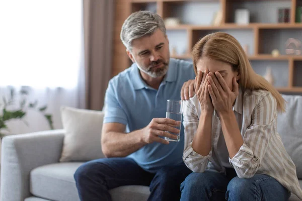 Serious Mature Caucasian Husband Calm Upset Crying Wife Gives Glass — Zdjęcie stockowe