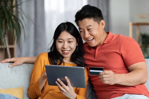 Excited Asian Husband Wife Embracing Using Digital Tablet Plastic Credit — Fotografia de Stock