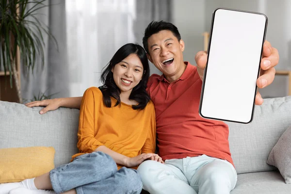Cheerful Chinese Lovers Man Woman Homewear Sitting Couch Embracing Showing — Stock fotografie