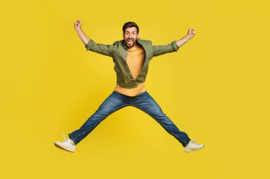 Expressing happiness. Full length studio shot of excited middle aged man jumping over yellow background. Happy male celebrating success or victory, copy space