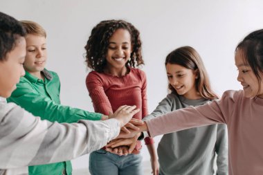 Unity And Friendship. Cheerful Preteen Children Putting Hands Together Posing Standing In Circle Indoors, Selective Focus. Kids Teamwork And Teambuilding Concept