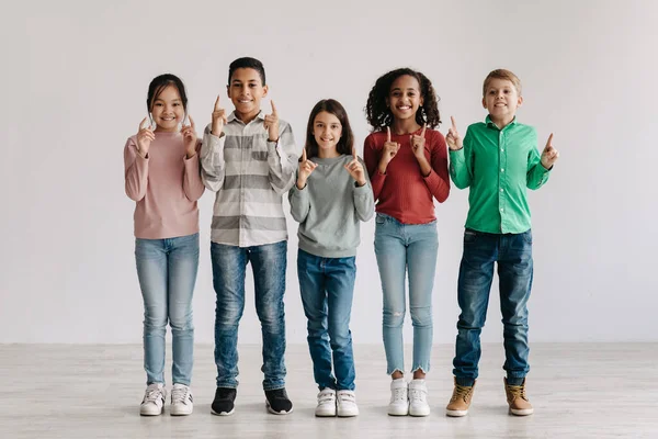 Look Cheerful Multicultural Preteen Children Pointing Fingers Upward Posing Standing — Stock Fotó