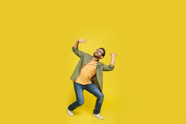 Stylish Man Holding Invisible Object Overhead Posing Isolated Yellow Studio — Stok fotoğraf
