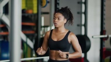 Sport training. Close up portrait of young concentrated black lady athlete exercising in gym, warming up her body, slow motion, free space