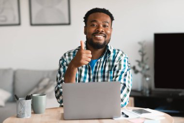 Black Man Freelancer At Laptop Computer Gesturing Thumbs Up Approving Website Sitting Working Online In Modern Office, Smiling To Camera. I Like Freelance And Entrepreneurship. Selective Focus