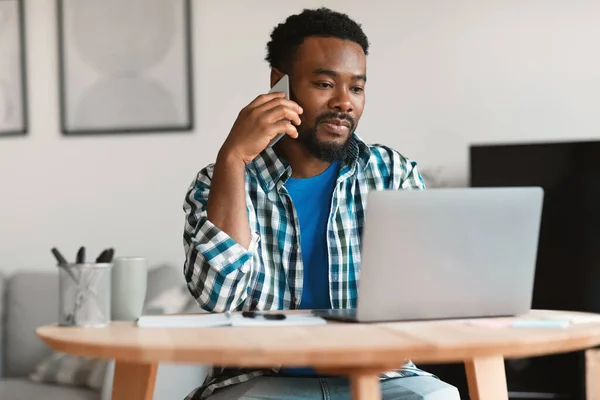 African American Freelancer Guy Calling Cellphone Working Online Laptop Communicating — стокове фото