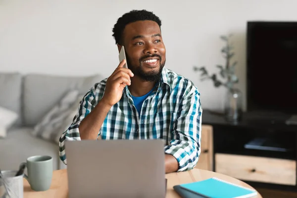 Cheerful Black Guy Talking Phone Using Laptop Working Online Sitting — Stock fotografie
