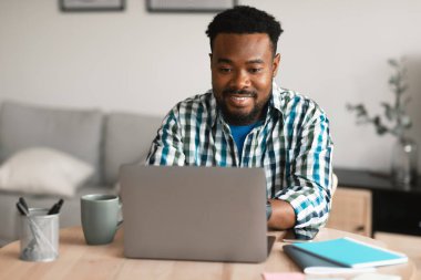 Successful African American Entrepreneur Man Using Laptop Computer Browsing Internet And Working Online Sitting At Home. Professional Freelance Career And Remote Job Concept