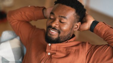 Relaxed Black Guy Resting With Eyes Closed Holding Hands Behind Head Sitting On Sofa At Home. Millennial Guy Relaxing On Weekend. Relaxation Leisure And Domestic Comfort. Panorama