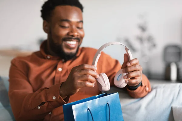 Happy African American Guy Unpacking Shopping Bag New Earphones Sitting — Stockfoto