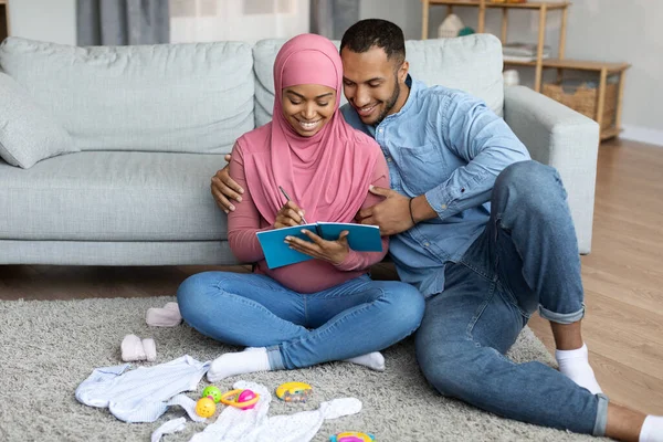 Preparing Childbirth Happy Pregnant Black Muslim Spouses Making Checklist Necessities — Zdjęcie stockowe