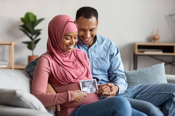 Black Pregnant Islamic Couple Holding Baby Ultrasound Scan While Sitting — Foto de Stock