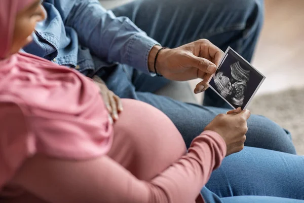 Pregnant Islamic Spouses Looking Baby Sonography Photo While Sitting Couch — Zdjęcie stockowe