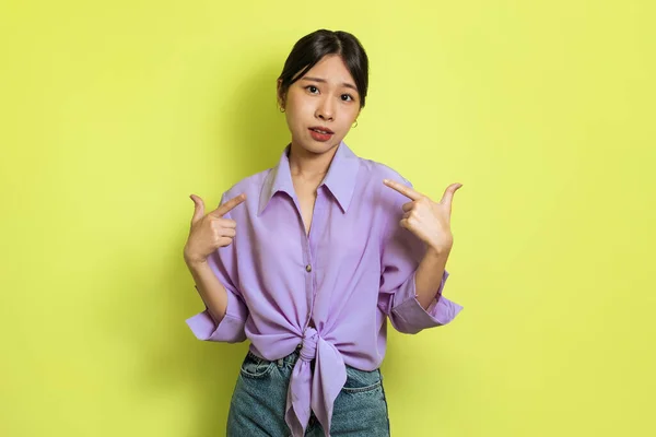 Low Self Esteem Problem. Sad Korean Female Pointing Fingers At Herself Looking At Camera Standing Posing Over Yellow Background. Look At Me Concept. Studio Shot