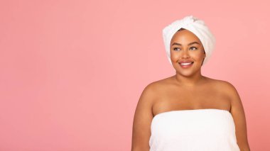 Beauty Care. Attractive Oversized African American Lady Wrapped In Towel Posing Standing Over Pink Studio Background, Smiling Looking Aside. Female Selfcare And Pampering. Panorama With Empty Space