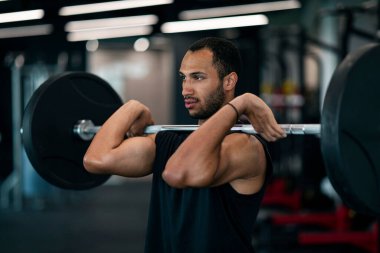 Young Black Male Athlete Working Out With Heavy Barbell At Gym, Handsome African American Sportsman Training Muscles At Modern Fitness Club Interior, Enjoying Bodybuilding, Closeup Portrait