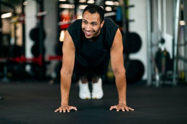 Sporty Black Male Making Straight Arm Plank Exercise While Training At Gym, Front View Of Handsome Young African American Athlete Doing Bodybuilding Workout In Modern Sport Club, Copy Space